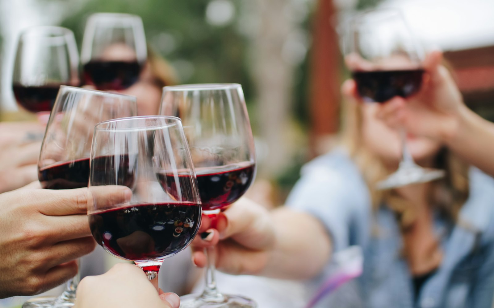 Varias copas de vino tinto en un brindis al aire libre