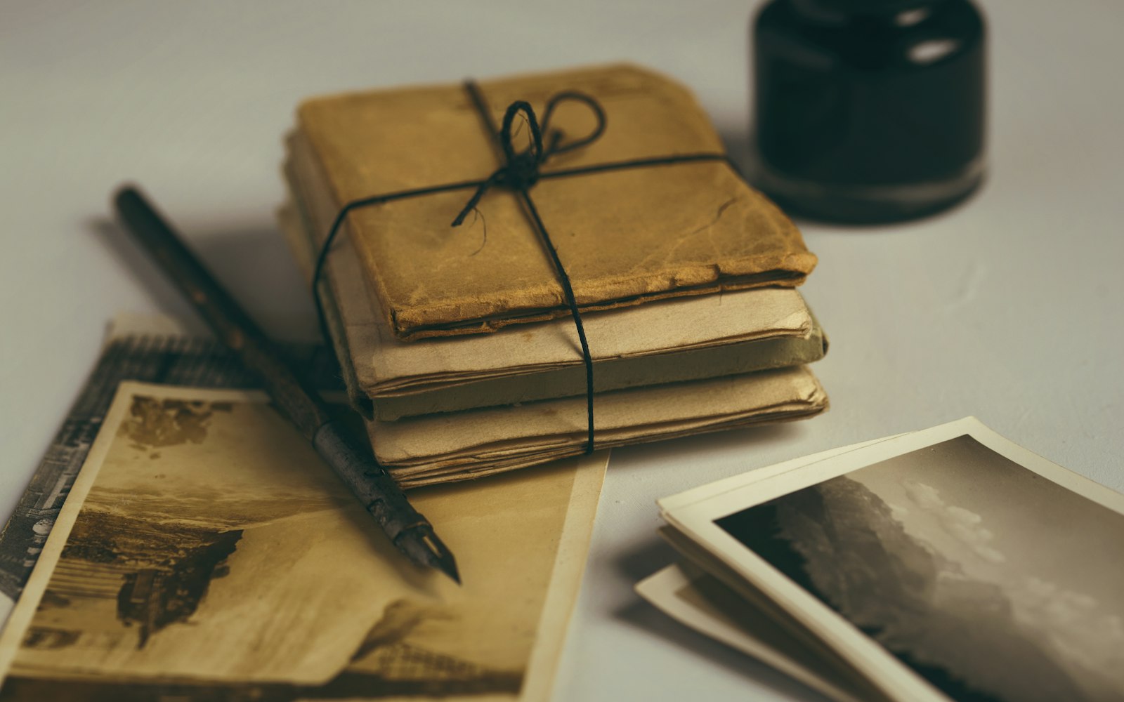 Cuadernos antiguos atados con un cordel, junto a una pluma